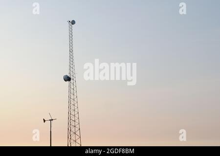 Sendemast mit Parabolantennen,Windrad mit Nabendynamo auf dem Parkplatz vor der Murphy`s Dome Air Force Station Militärbasis in Fairbanks,Alaska,USA. Stockfoto